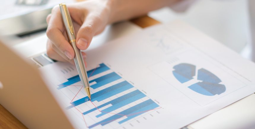 Business woman hand with Financial charts and laptop on the table